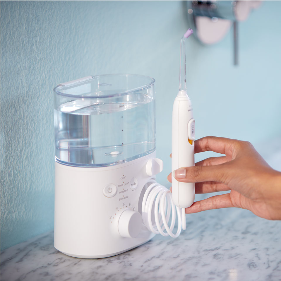Hand reaching for a Power Flosser device on a countertop