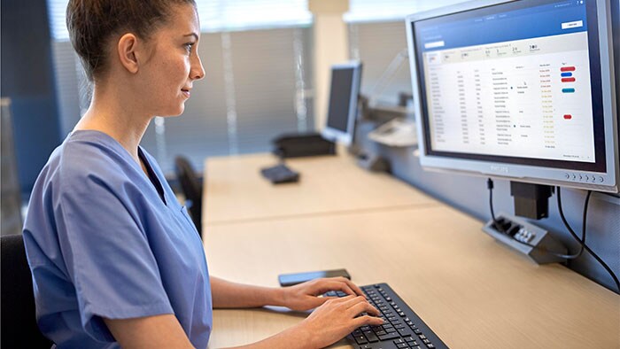 clinician looking at the screen while typing with a keyboard and filling in data