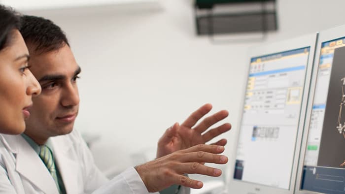 Photo of clinicians conferring about CT results on a computer monitor