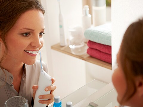 Lady using the electric flosser on her teeth