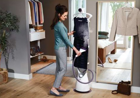Lady using the standing clothes steamer on a dress