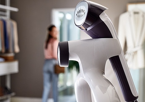 Handheld clothes steamer resting on its stand