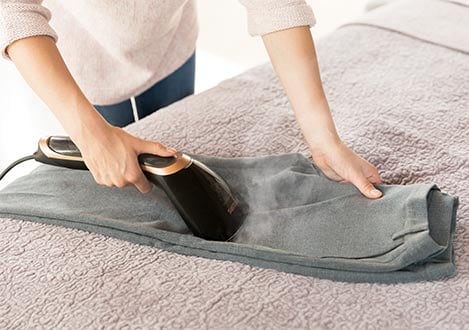 Steam&Go Handheld steamer being used on pants horizontally