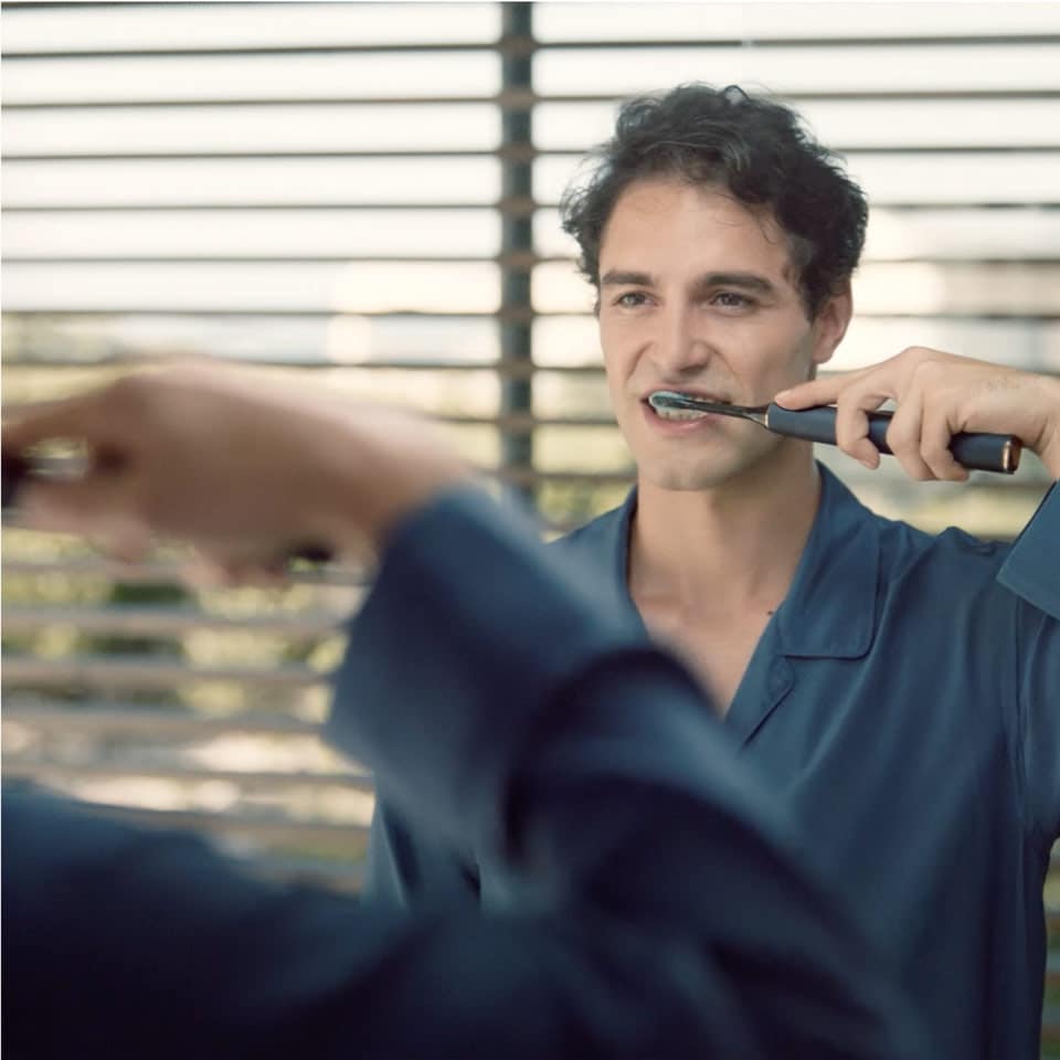 Man using a DiamondClean Smart with Premium Plaque Control brush head looking in a mirror