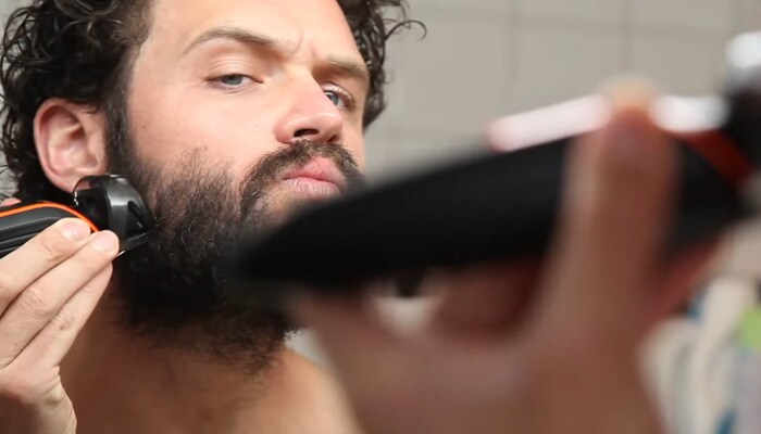 Man preparing to trim handlebar moustache by shaving beard